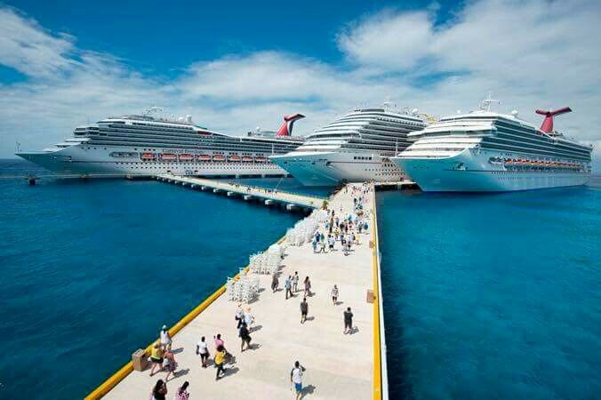 two cruise ships docked in the ocean with people walking on it's dock area