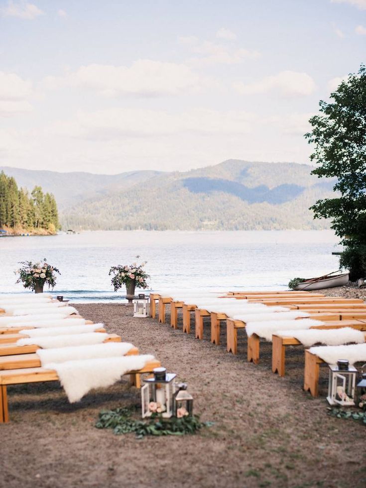 rows of wooden benches lined up next to the water with flowers in vases on them