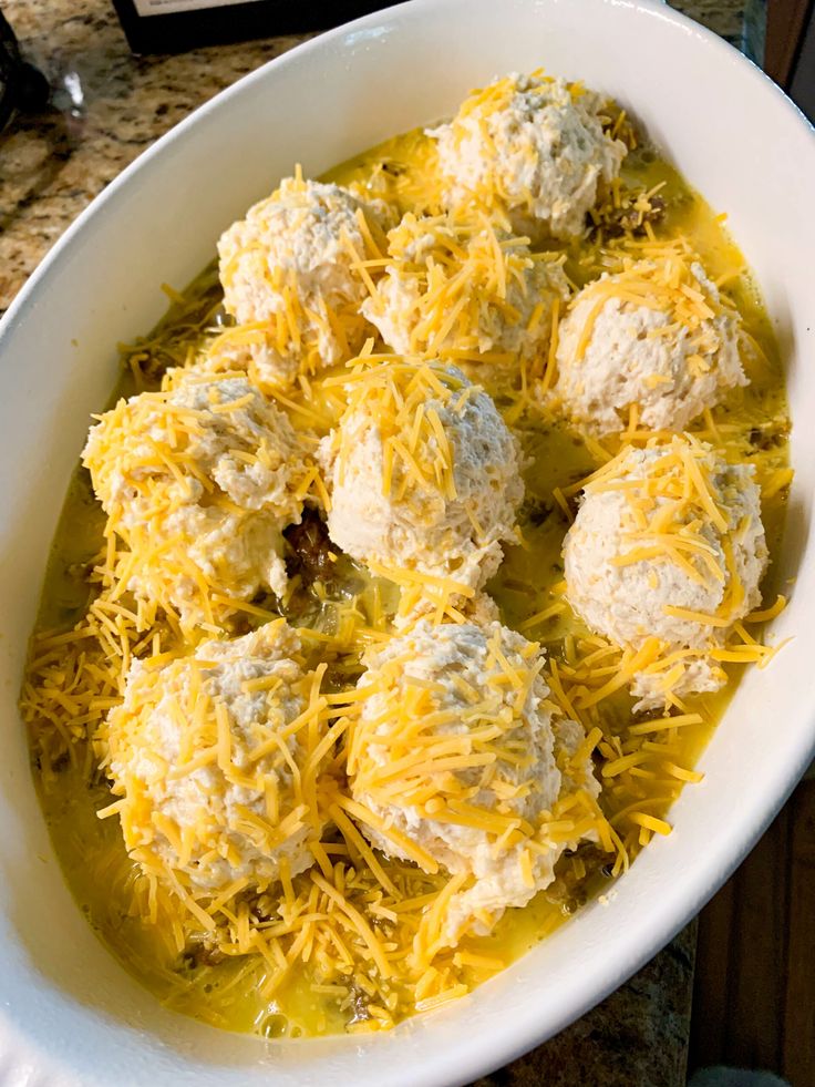 a white bowl filled with cheese covered meatballs