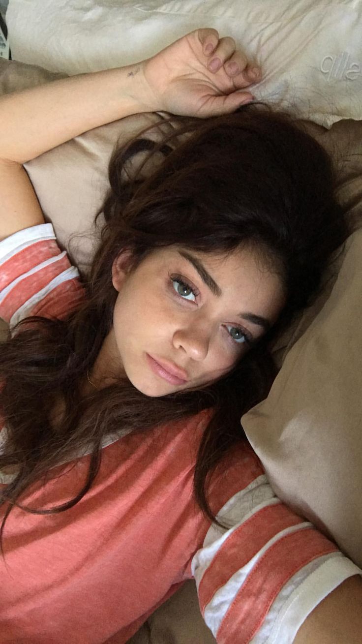 a young woman laying on top of a bed next to pillows