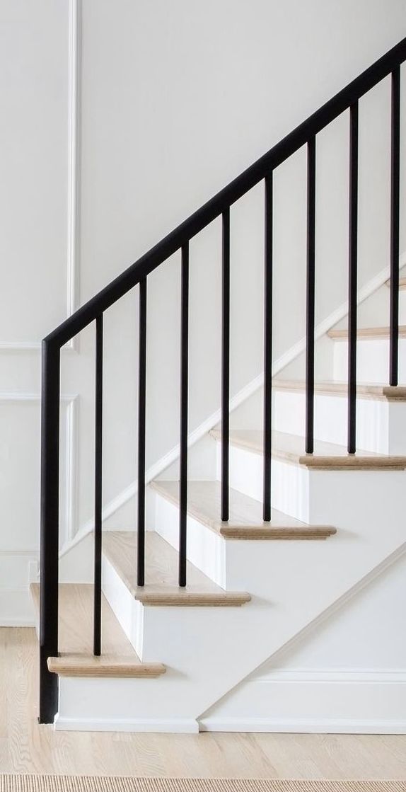 a white staircase with black handrails in an empty room