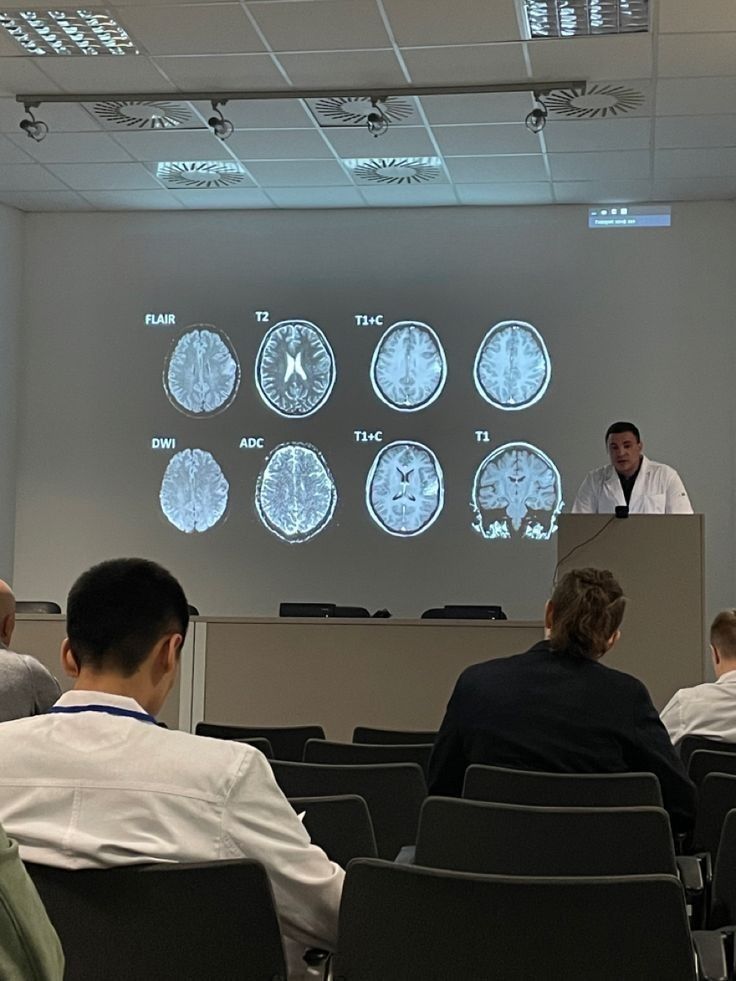 a man is giving a presentation in front of an audience with mri images on the wall