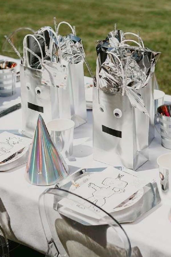 some silver bags are sitting on a table with other items around it and there is a party hat in the middle