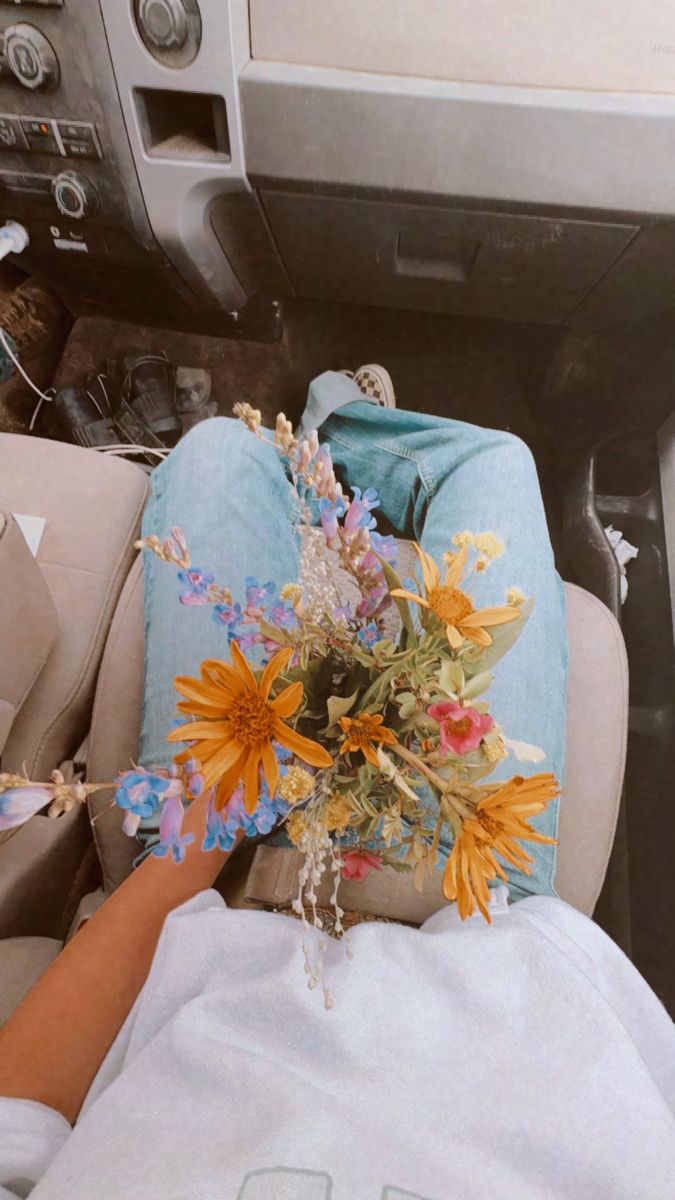 a person laying in the back seat of a car with a bouquet of flowers on their lap