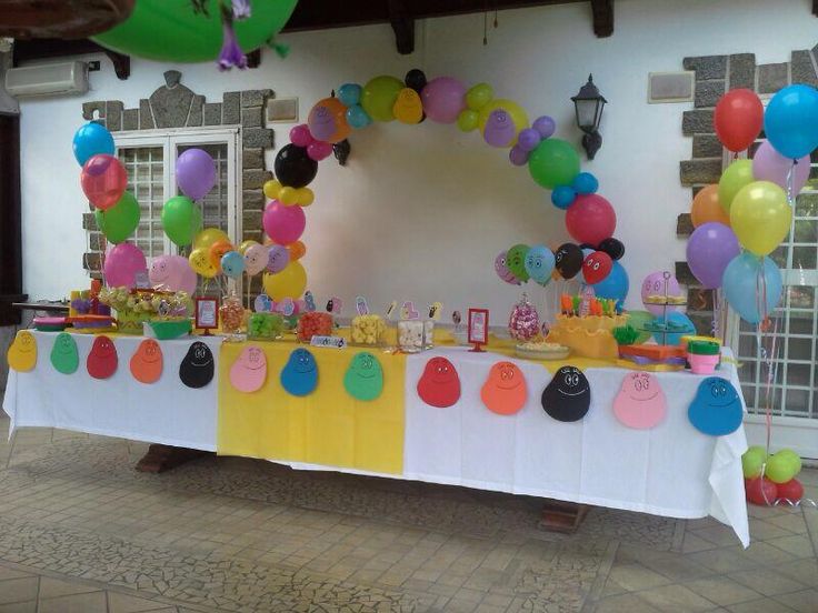 a table topped with lots of balloons next to a white table covered in cake and candy