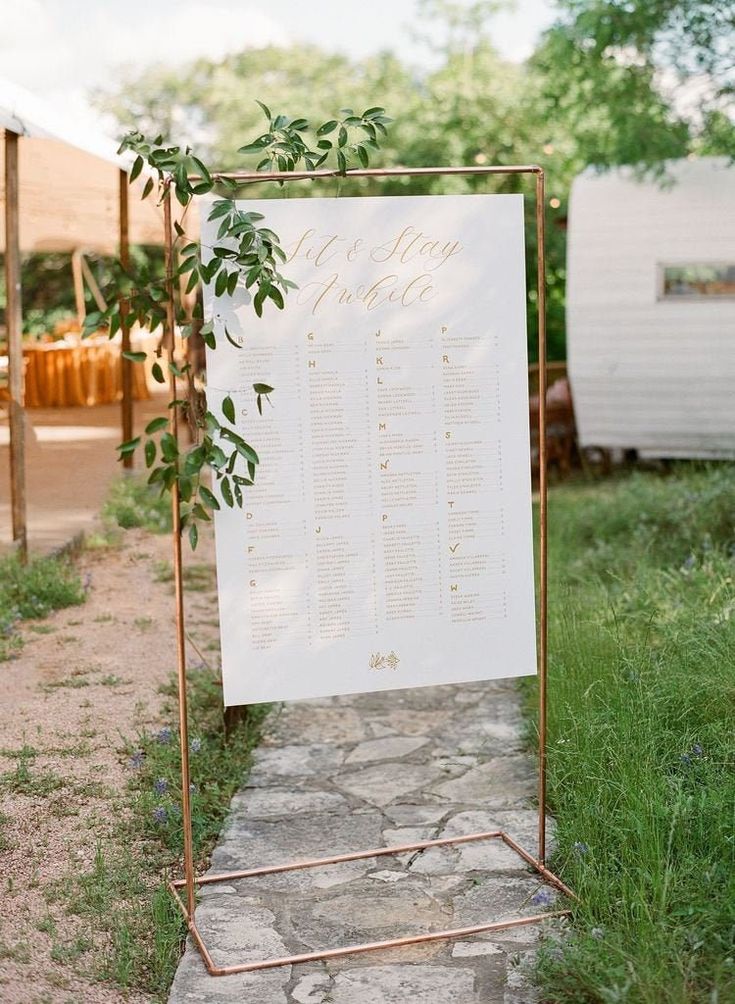 a sign that is sitting in the grass next to a stone path with greenery on it