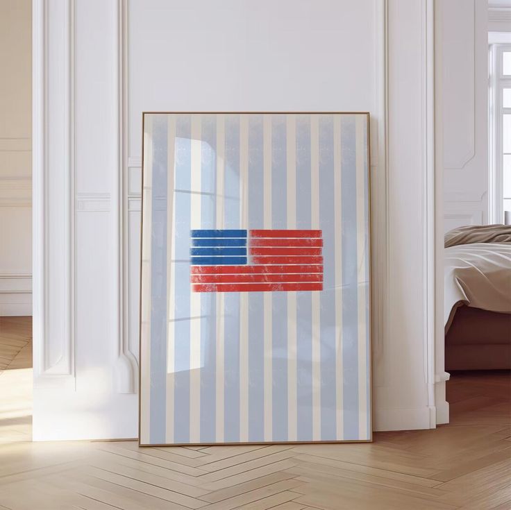 an american flag is hanging on the wall next to a bed in a room with white walls