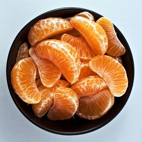 peeled oranges in a black bowl on a white table