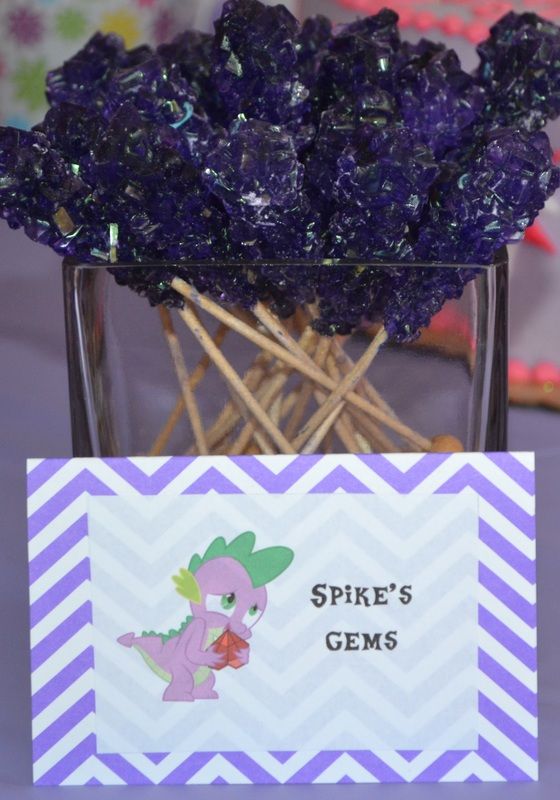 some purple rocks are in a glass vase on a table with a sign that says spike's gems