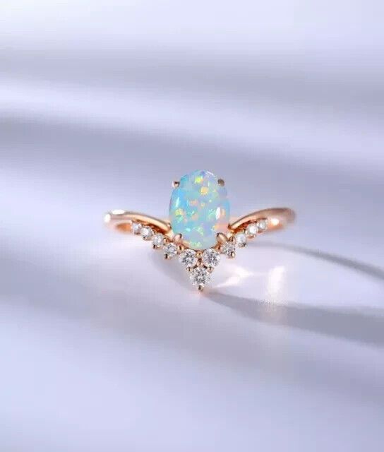 a white opal and diamond ring on a white surface with the light shining through it