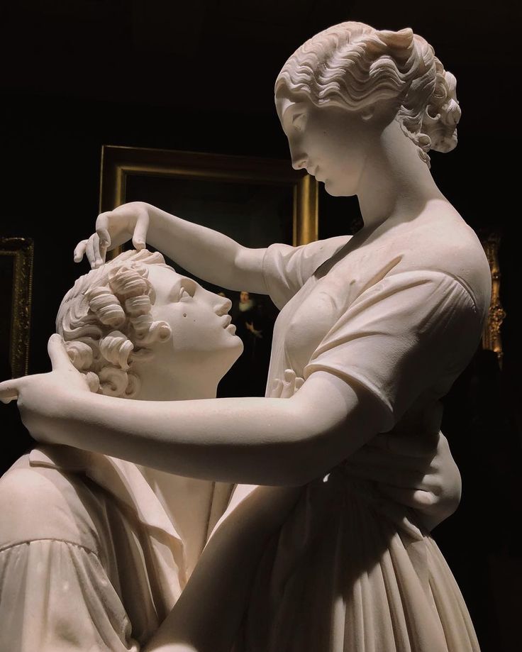 a statue of two women touching each other's hands in front of a mirror