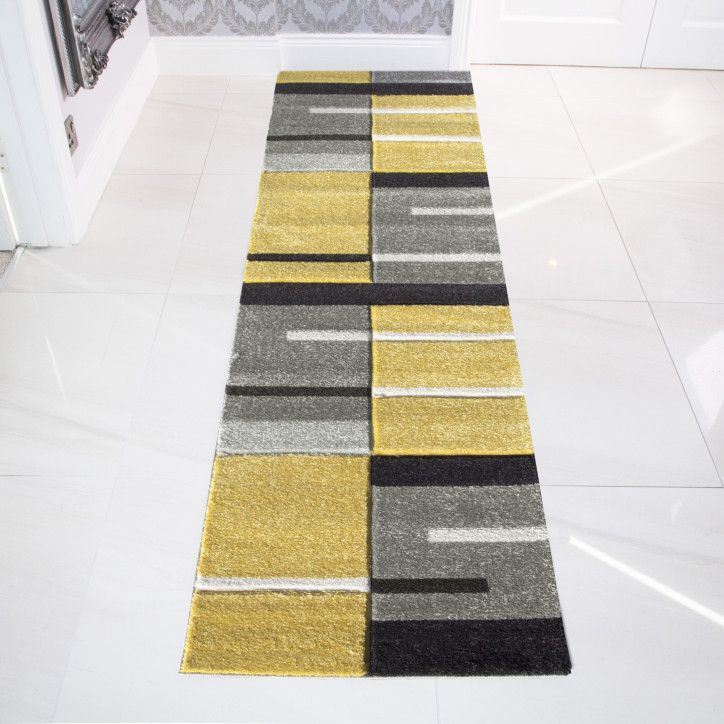 a yellow, black and grey rug on the floor in front of a white door