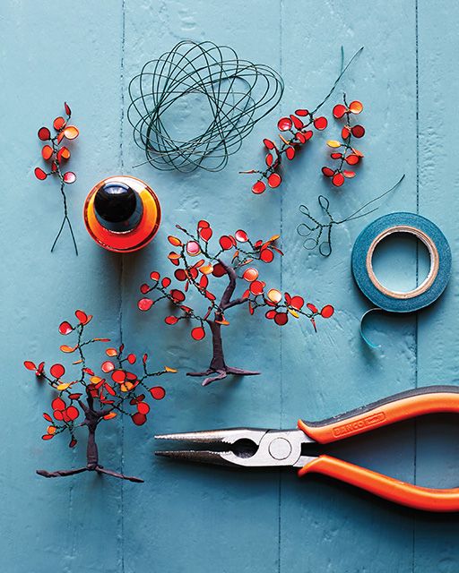 scissors, wire and other crafting items on a blue surface with red berries in the center