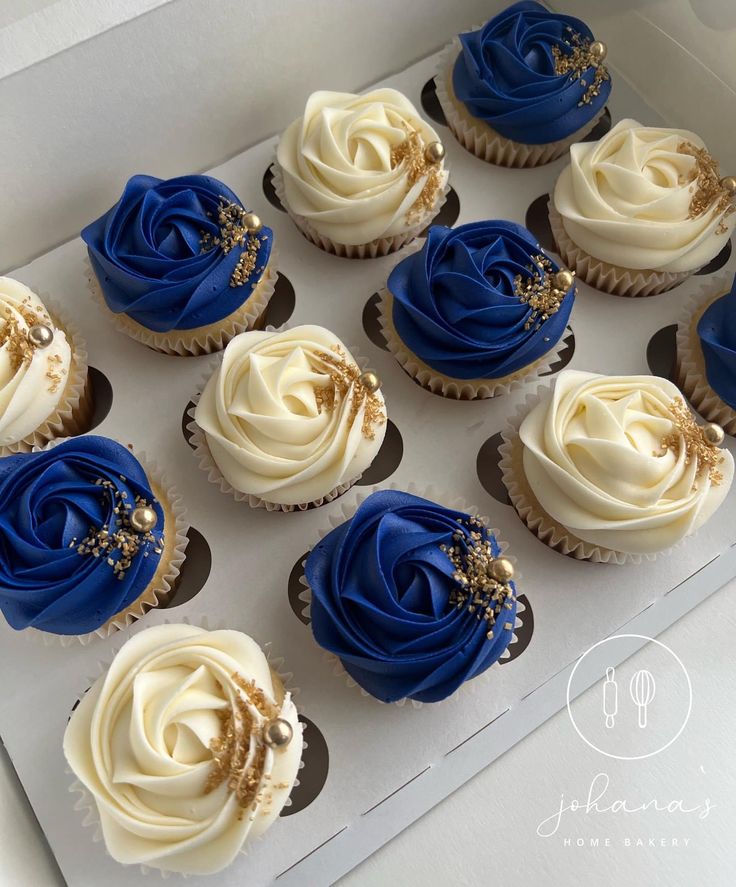 twelve cupcakes with blue and white frosting in a box