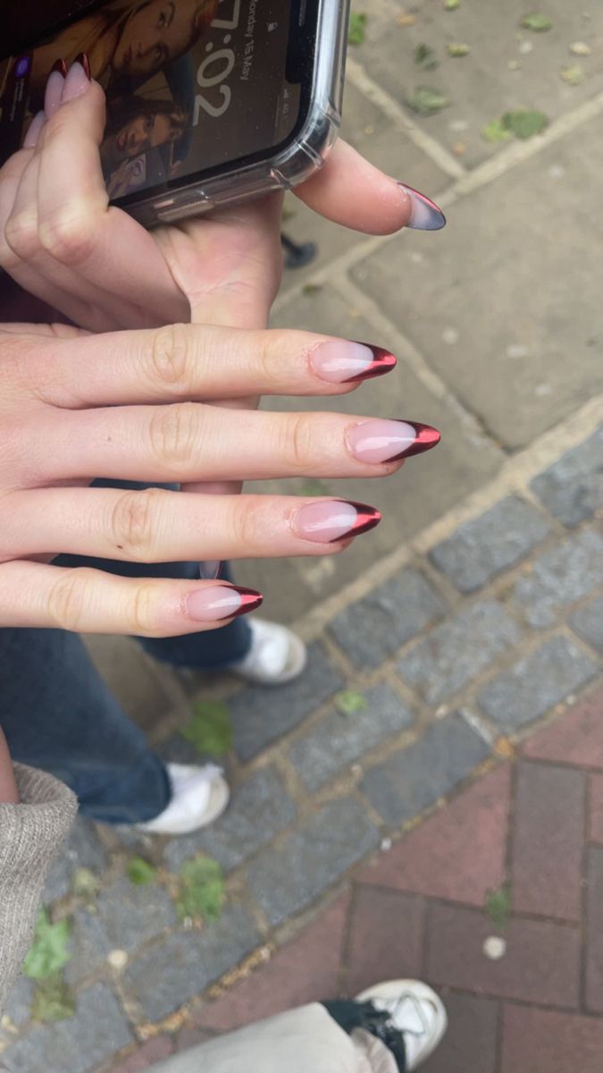 a woman with red and white nails holding up her cell phone