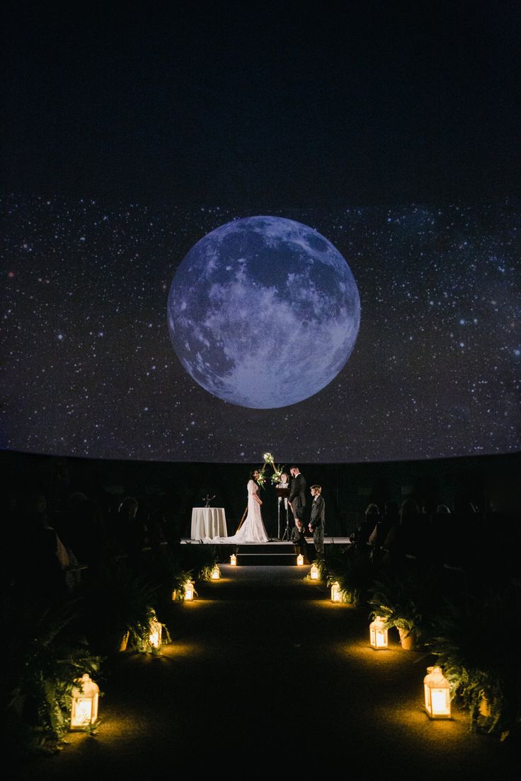 a bride and groom are standing under the moon