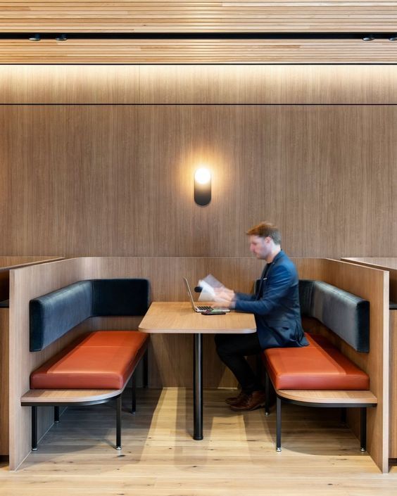 a man sitting at a table in front of a laptop computer on top of a wooden bench