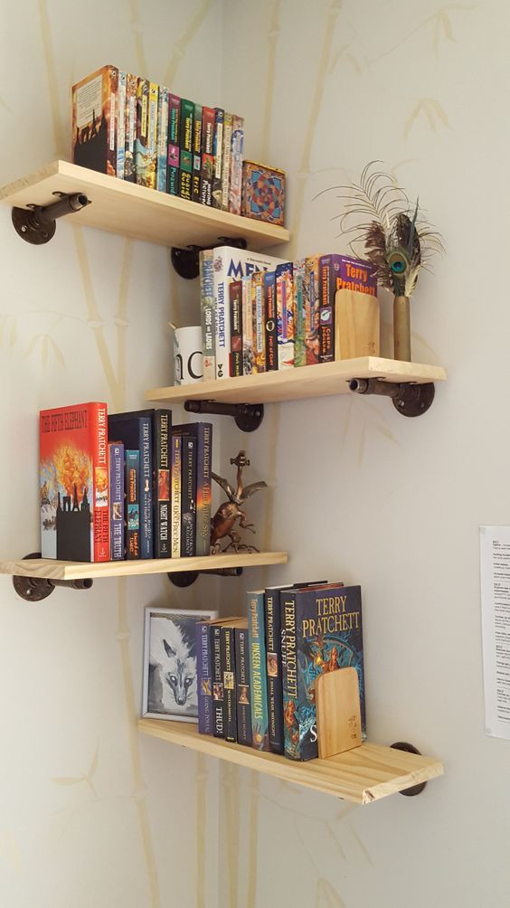 three wooden shelves filled with books on top of each other next to a white wall