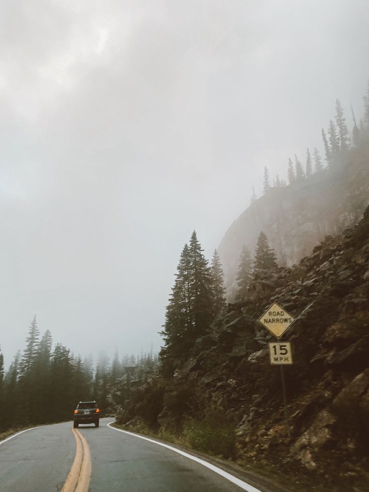 the car is driving down the mountain road