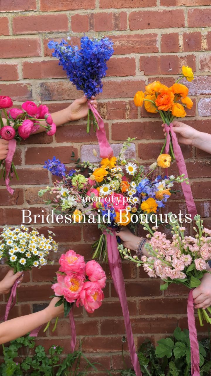 the bridesmaid bouquets are being held up against a brick wall by their hands