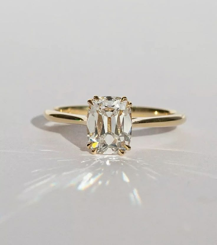 a yellow gold ring with an oval cut diamond in the center, on a white surface