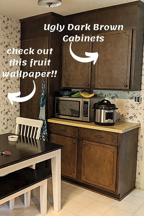 a kitchen with dark brown cabinets and white table