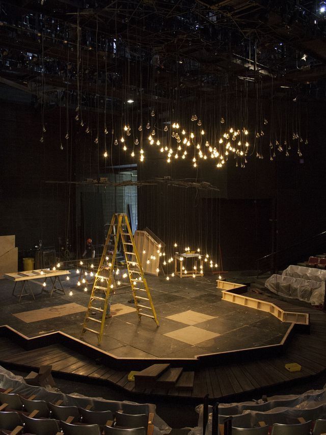 an empty stage with ladders and lights hanging from it's ceiling in the dark