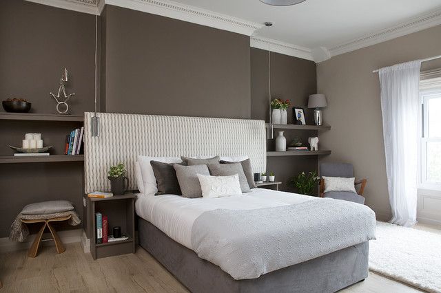 a bedroom with a large bed and shelves on the wall, along with two chairs