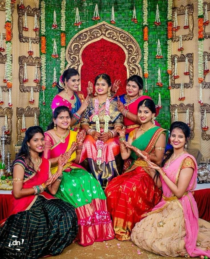 a group of women sitting next to each other in front of a decorated stage with flowers