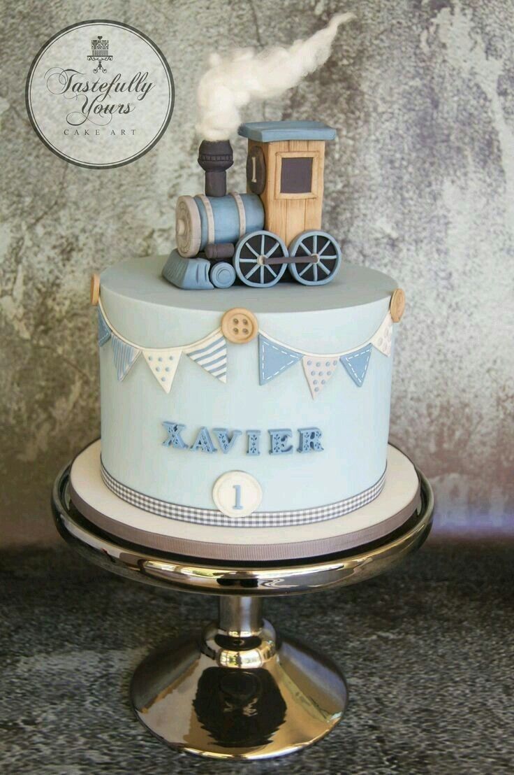 a blue cake with a train on top and bunting around the edges that says kavrer