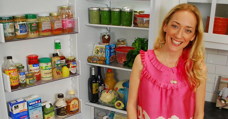 a woman standing in front of an open refrigerator with lots of food on the shelves