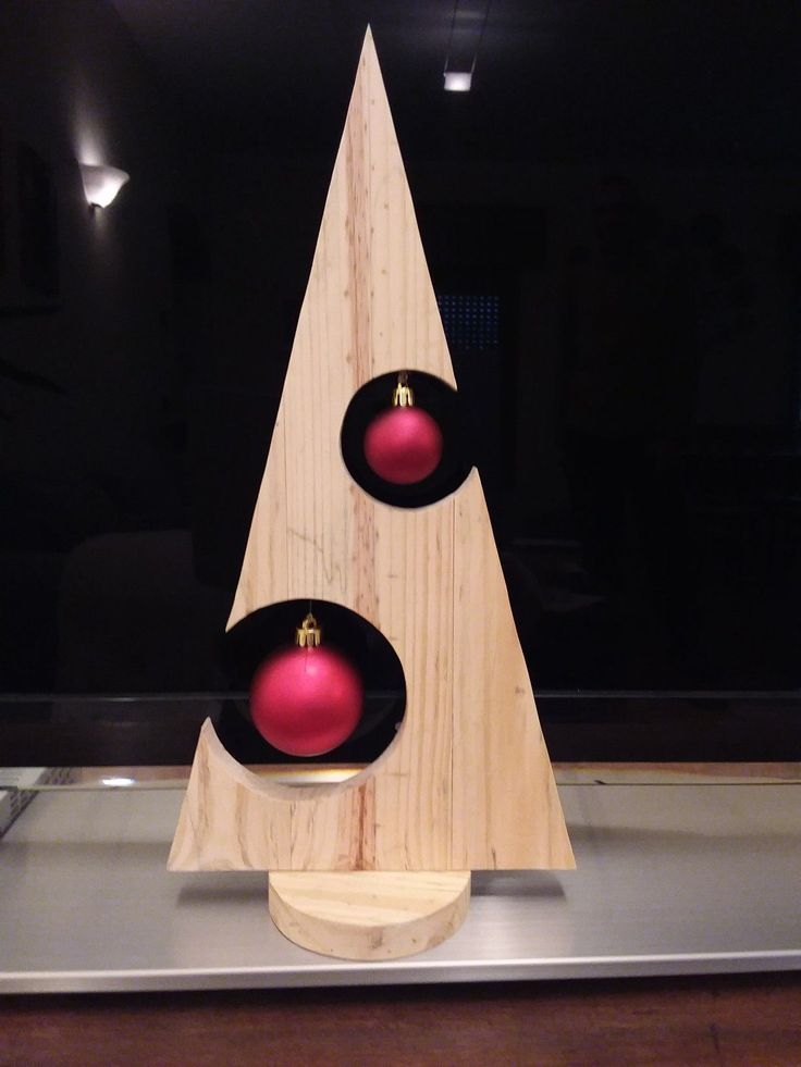 a wooden christmas tree with two red ornaments on it's top and one in the middle