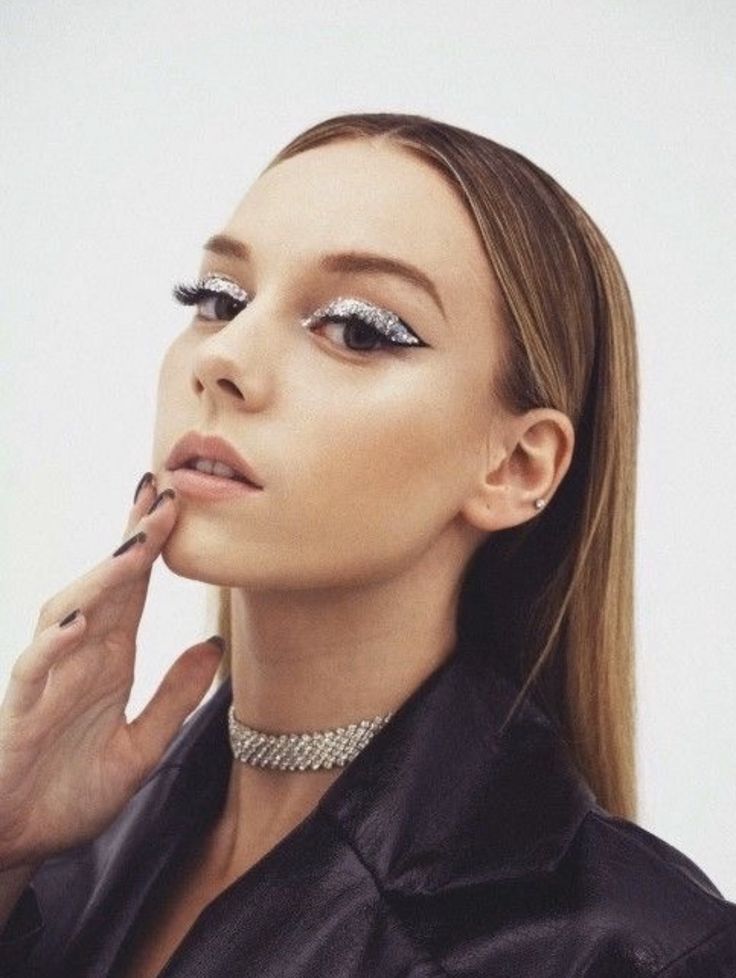 a woman with long hair and silver eyeshades is posing for the camera while holding her finger to her lips