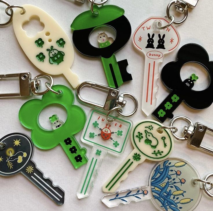 many different key chains are arranged together on a white surface, with green and black keys in the middle