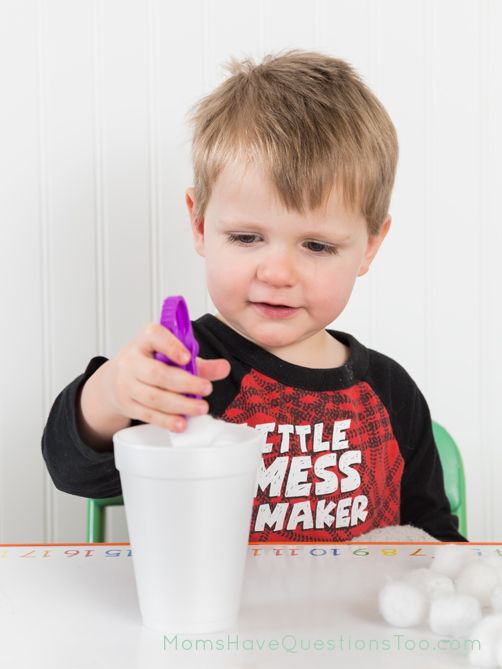 a little boy sitting at a table with a cup in front of him and marshmallows on the table