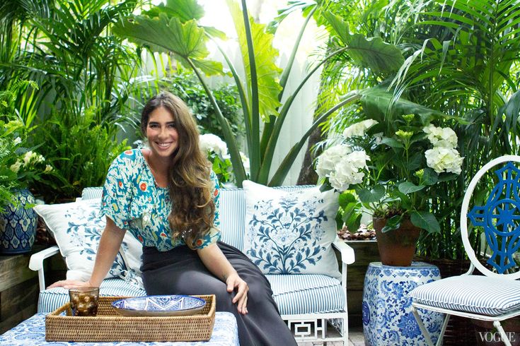 a woman sitting on top of a blue and white couch next to potted plants