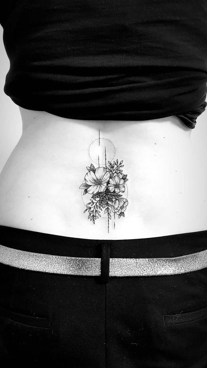 a woman's lower back tattoo with flowers on her stomach and behind her is a black - and - white photo