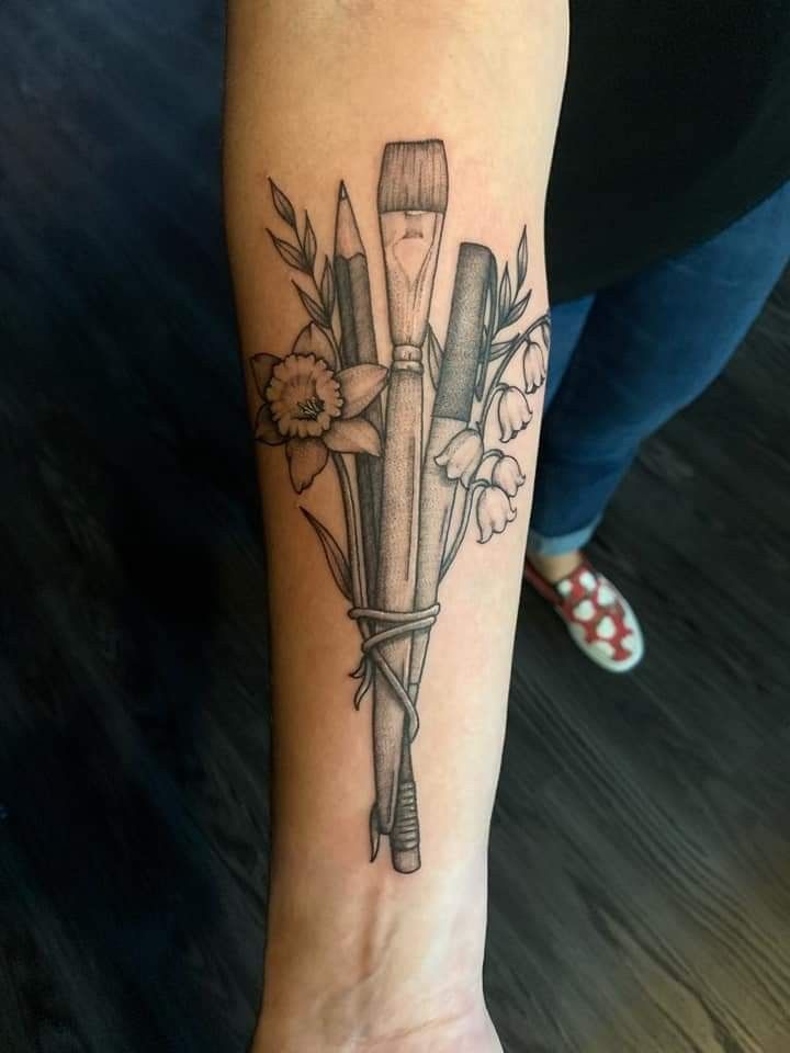 a woman's foot with a tattoo on it that has flowers and brushes in it