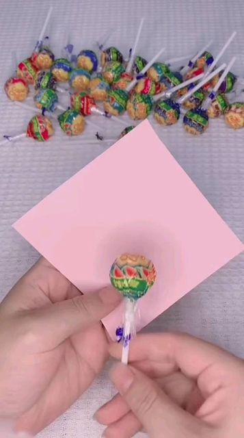 someone holding a candy lollipop in their hand and some candies on the table