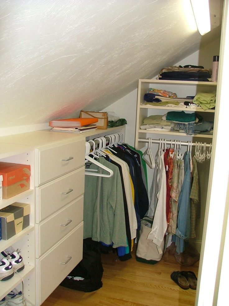 an attic closet with clothes and shoes on the shelves