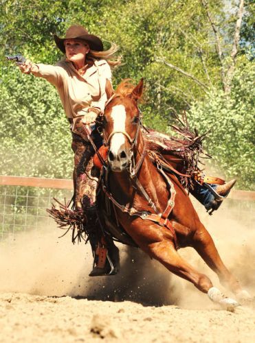 a woman riding on the back of a brown horse next to a fence and trees