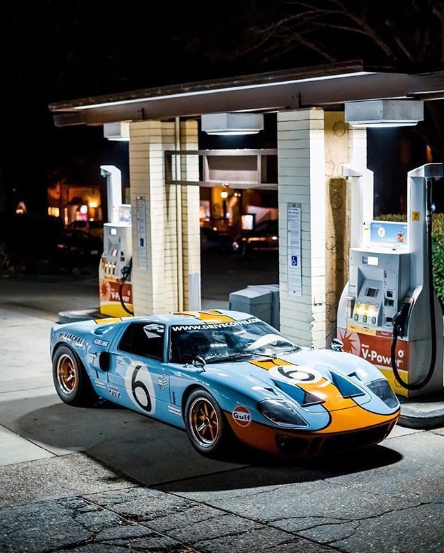 a blue and yellow race car parked at a gas station next to a fuel pump