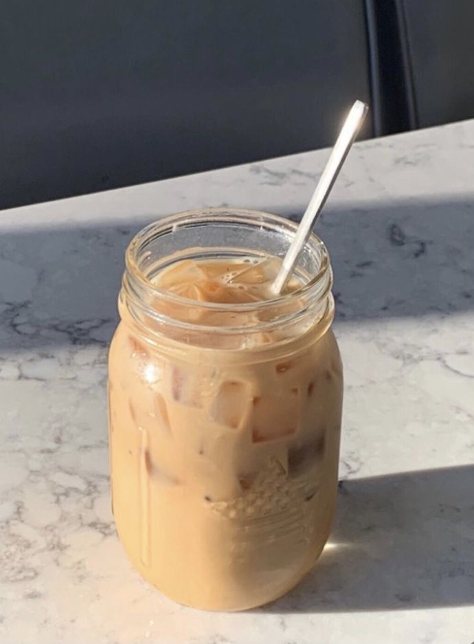 a glass jar filled with liquid sitting on top of a table next to a spoon