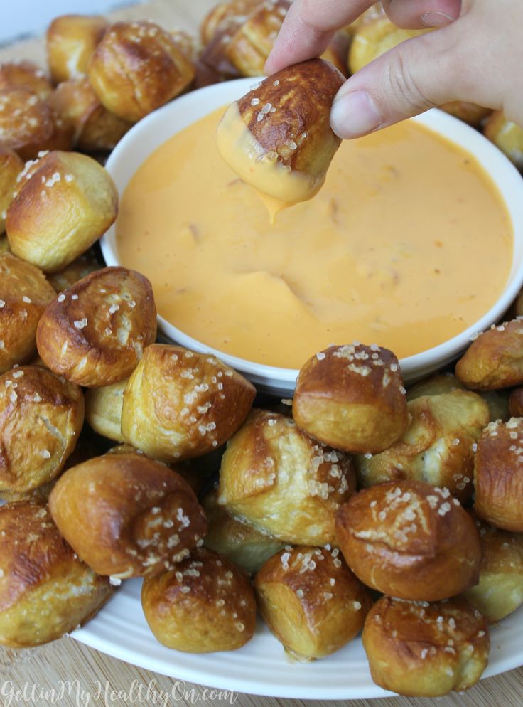 a person dipping sauce into some bread rolls