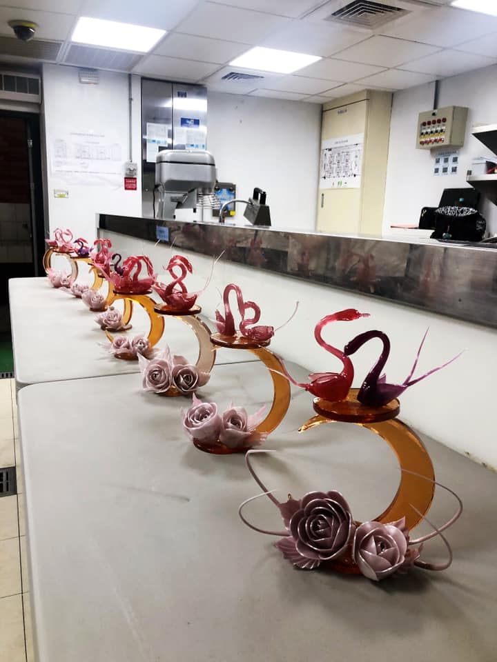 some pink flowers are sitting on the counter in front of a restaurant worker's desk