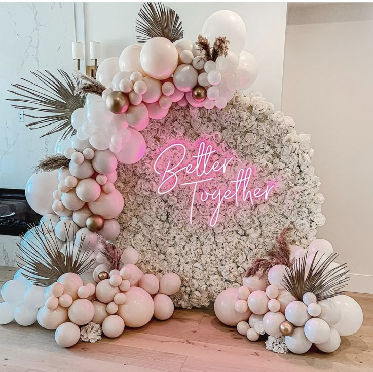 a pink and white balloon arch that says better together with balloons all over the place