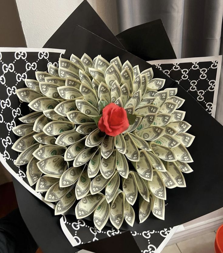 an origami flower made out of dollar bills on top of a black table