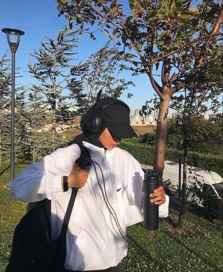 a man wearing headphones and carrying a backpack while standing next to a lamp post