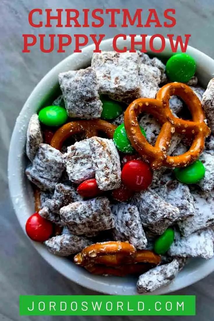 a bowl full of christmas puppy chow with candy and pretzels in the middle