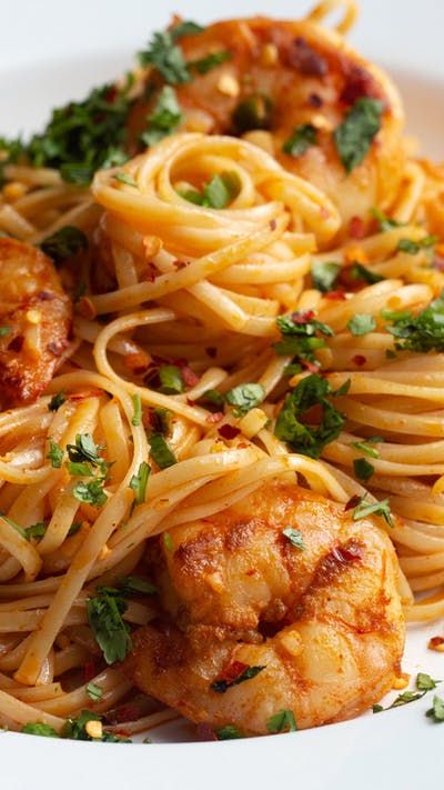 a white plate topped with pasta and shrimp